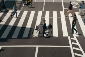 Cyklister och gående korsar ett brett övergångsställe i stadstrafik