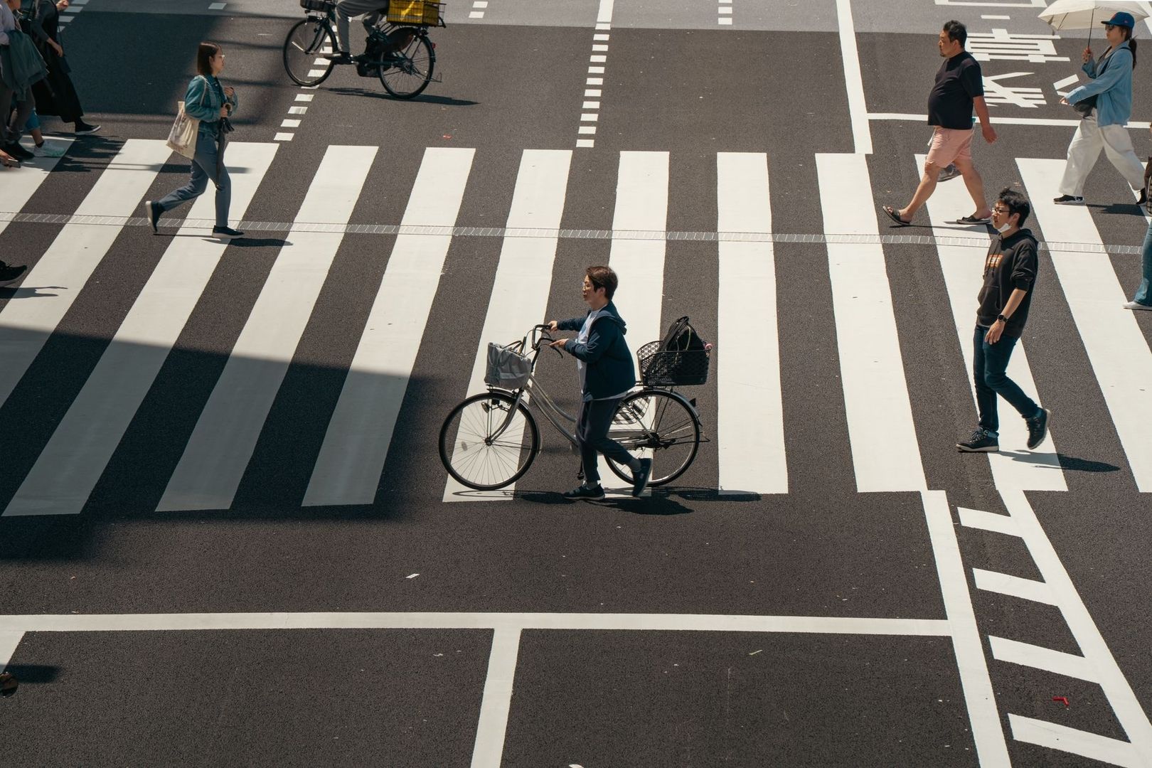 Cyklister och gående korsar ett brett övergångsställe i stadstrafik