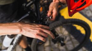 Person justerar bromsvajern på ett cykelstyre med verktyg