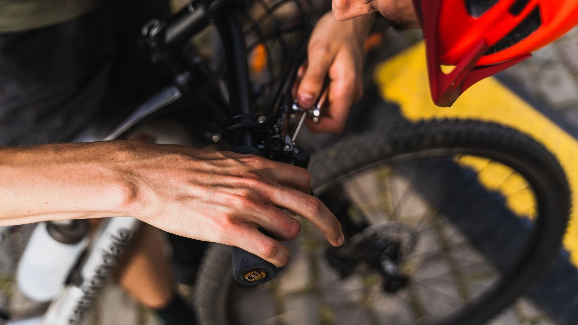 Person justerar bromsvajern på ett cykelstyre med verktyg