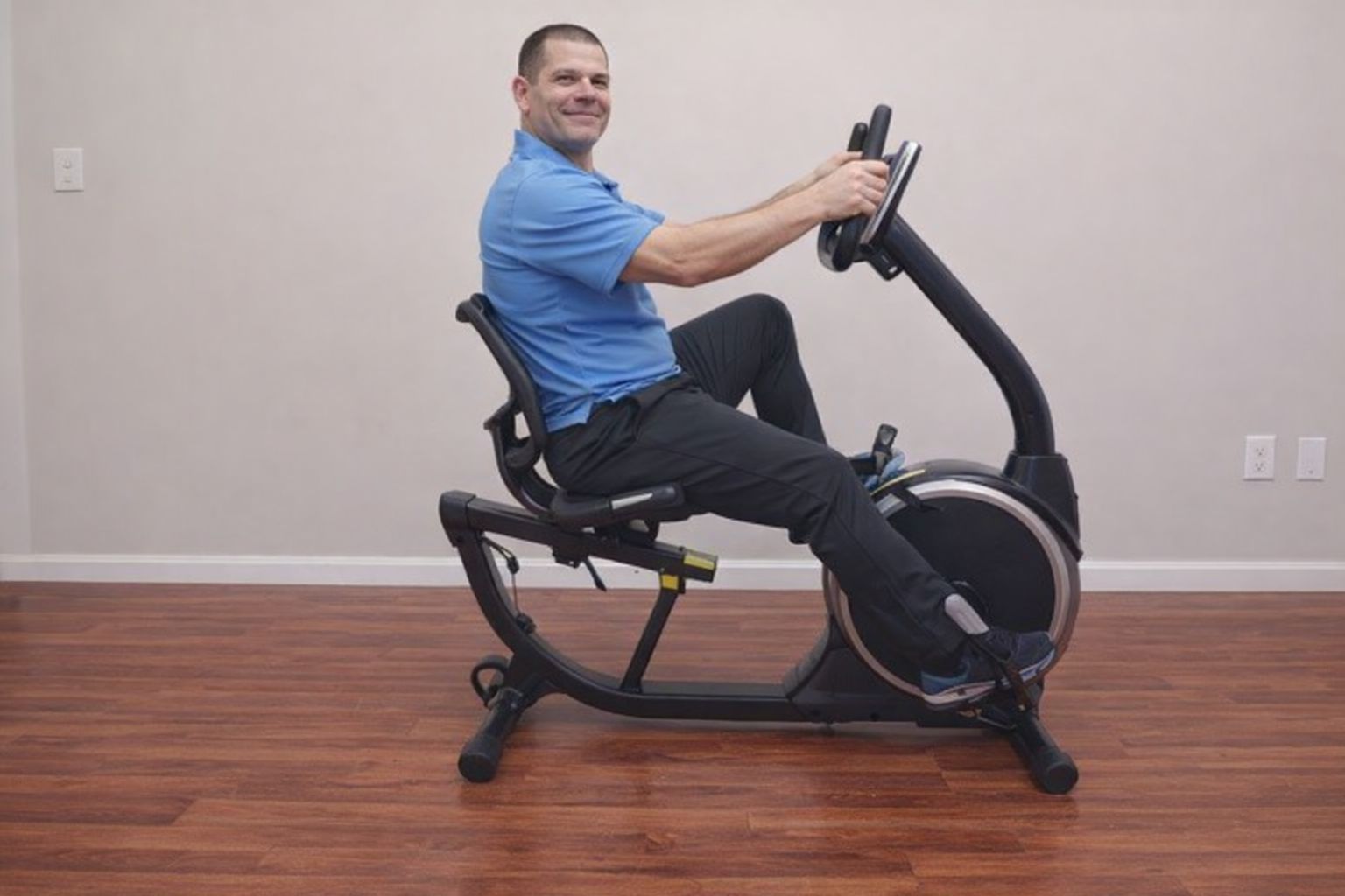 En man tränar på en sittcykel inomhus för hemmaträning.